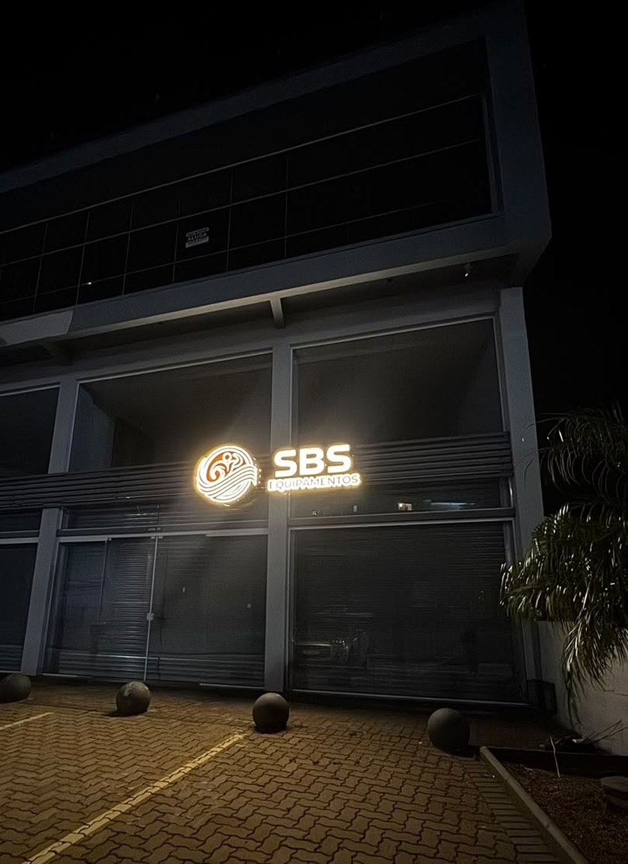 Fachada da loja SBS Equipamentos em Caxias do Sul à noite, com o letreiro iluminado